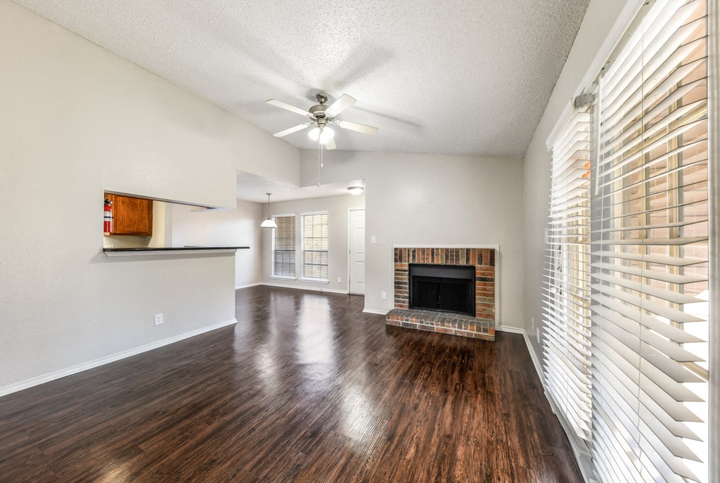 an empty living room with a fireplace and a ceiling fan
