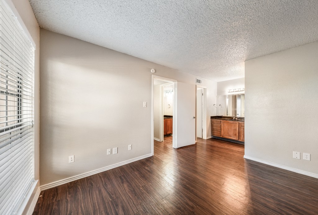 an empty living room with hard wood flooring and a window