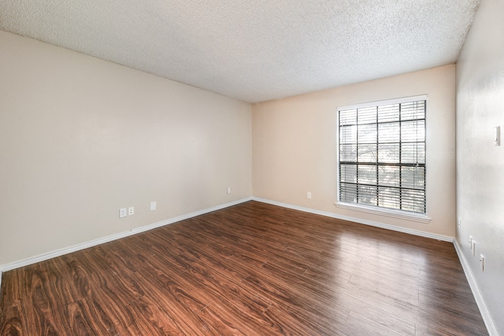 an empty living room with wood flooring and a window