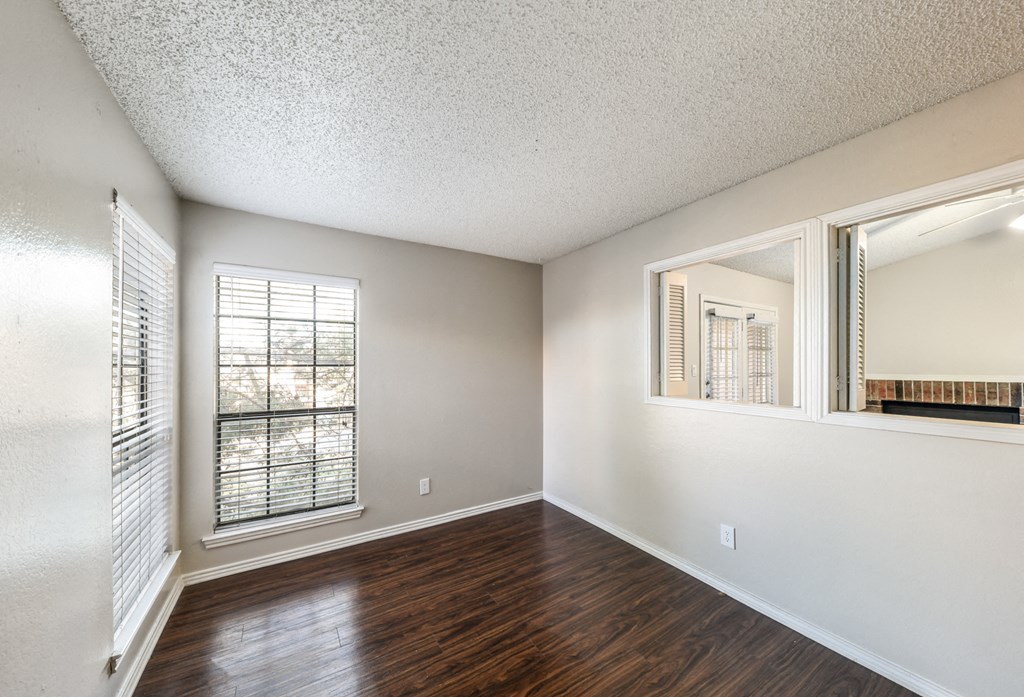 an empty living room with wood flooring and a window