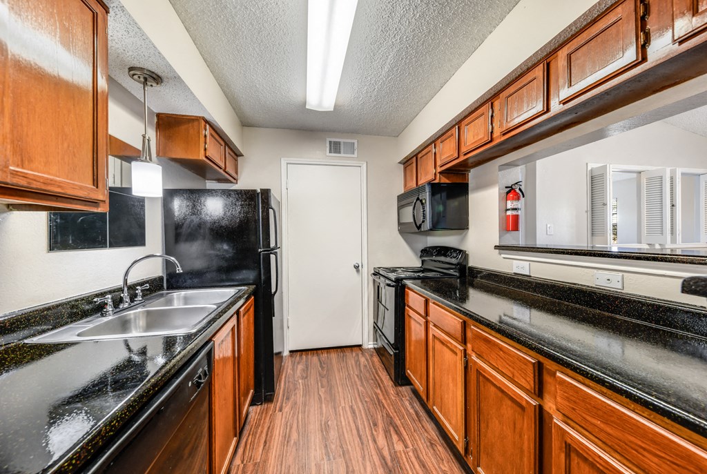 a kitchen with black counter tops and wooden cabinets