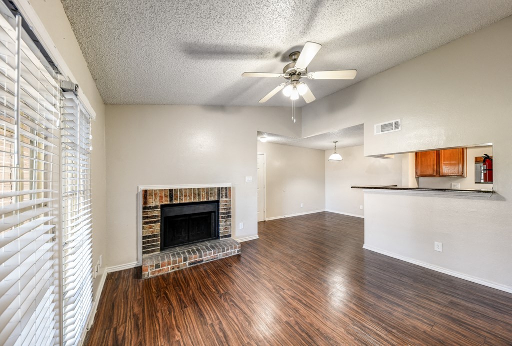 an empty living room with a fireplace and a ceiling fan