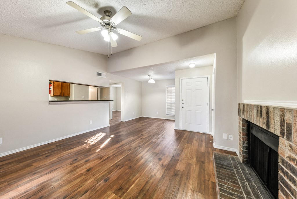 an empty living room with a fireplace and a ceiling fan