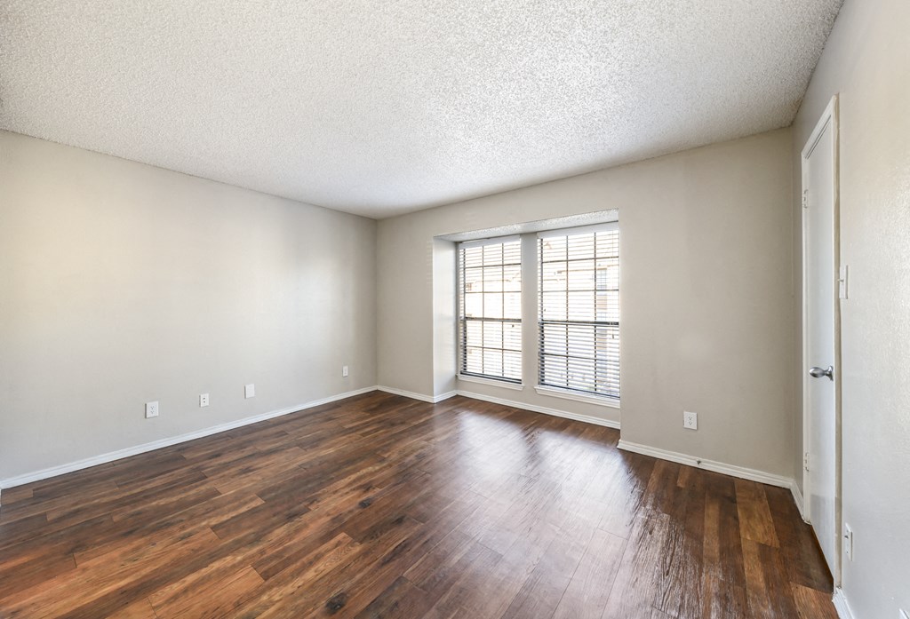 an empty living room with wood flooring and a large window