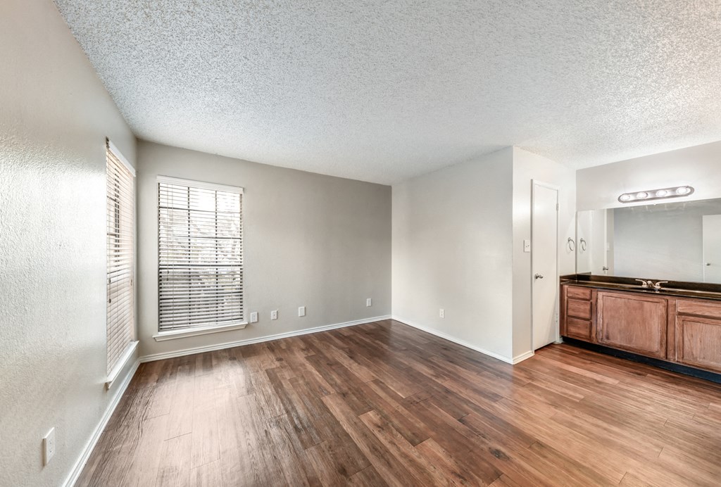 an empty living room with wood flooring and a window