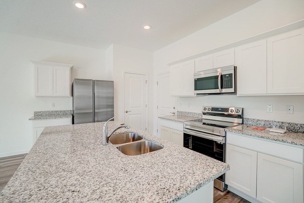 Kitchen with granite counter tops and stainless steel appliances in the Verbena floor plan at Beacon at Clinton Corners in Dade City, FL