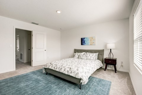Alternate view of master bedroom with blue rug and bed at Beacon at Arbours in Ruskin, FL