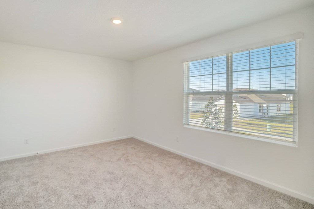 Bedroom with large window in the Verbena floor plan at Beacon at Clinton Corners in Dade City, FL