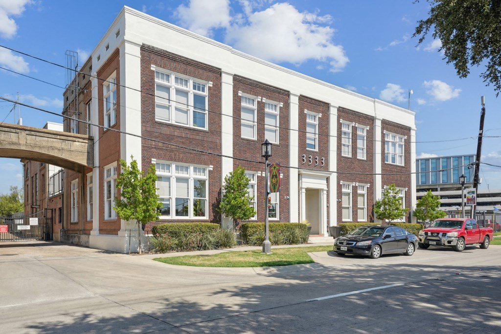 Street view of historic 3333 Elm Street Lofts Building with brick accents and large windows | Deep Ellum Lofts in Dallas, TX