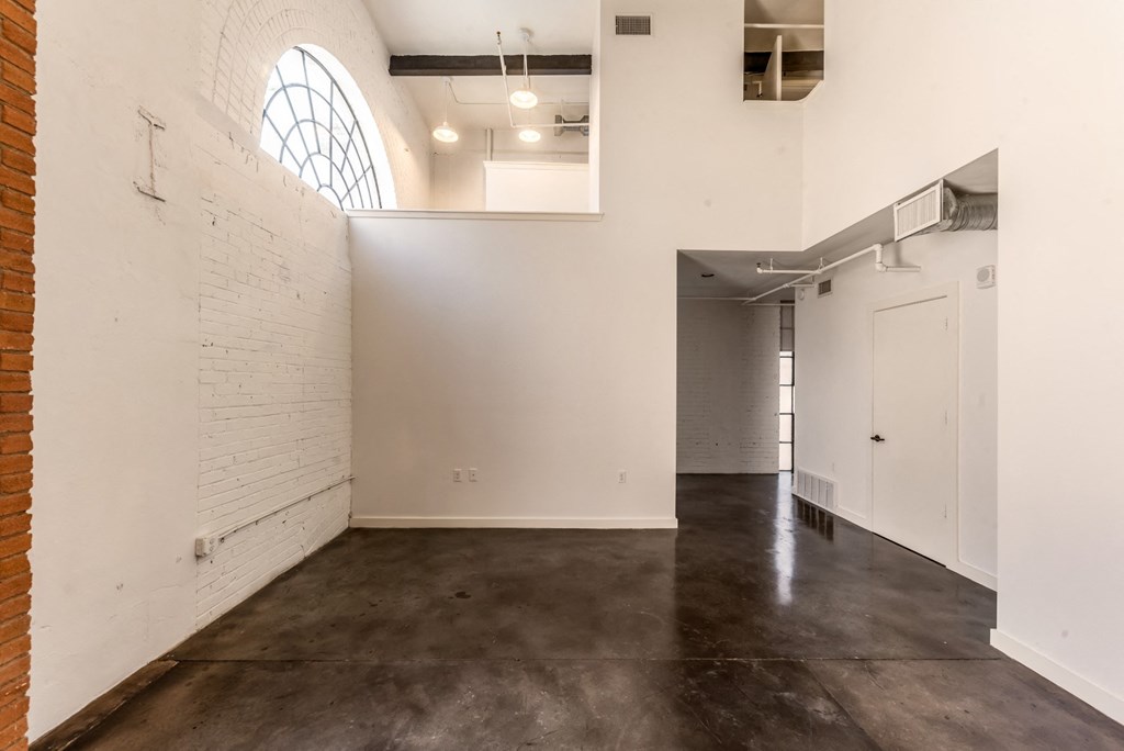 3333 Elm Street Lofts studio with spacious interiors, brick accent walls, and arched window at Deep Ellum Lofts in Dallas, TX