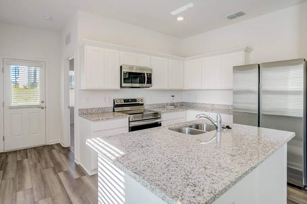 Kitchen with granite counter tops and kitchen island in the Elm floor plan at Beacon at Clinton Corners in Dade City, FL