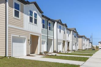 a row of townhomes with tan siding and white doors