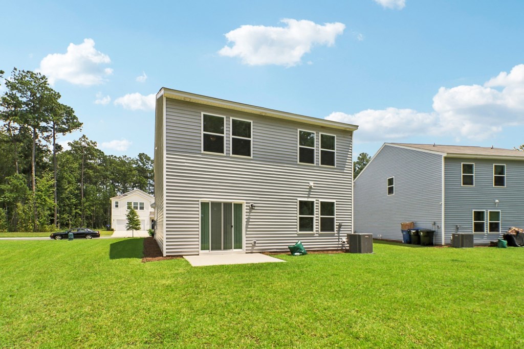 Spacious backyard with a well-maintained lawn and sliding glass doors at Beacon at Ashley River Landing in Summerville, SC