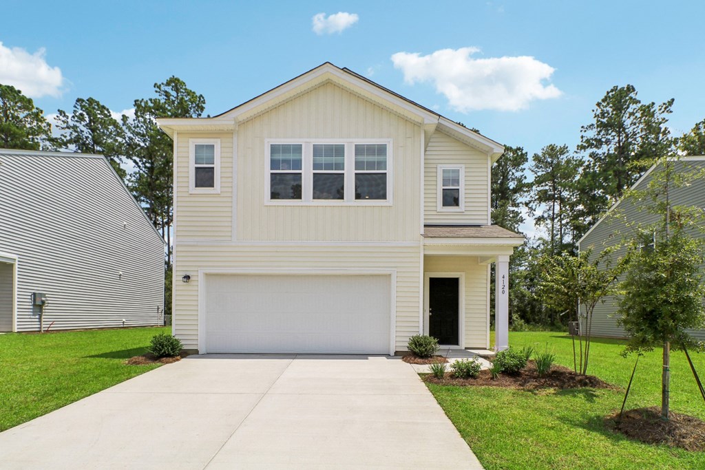 Front exterior view of the apartment with a two-car garage and well-kept lawn at Beacon at Ashley River Landing in Summerville, SC