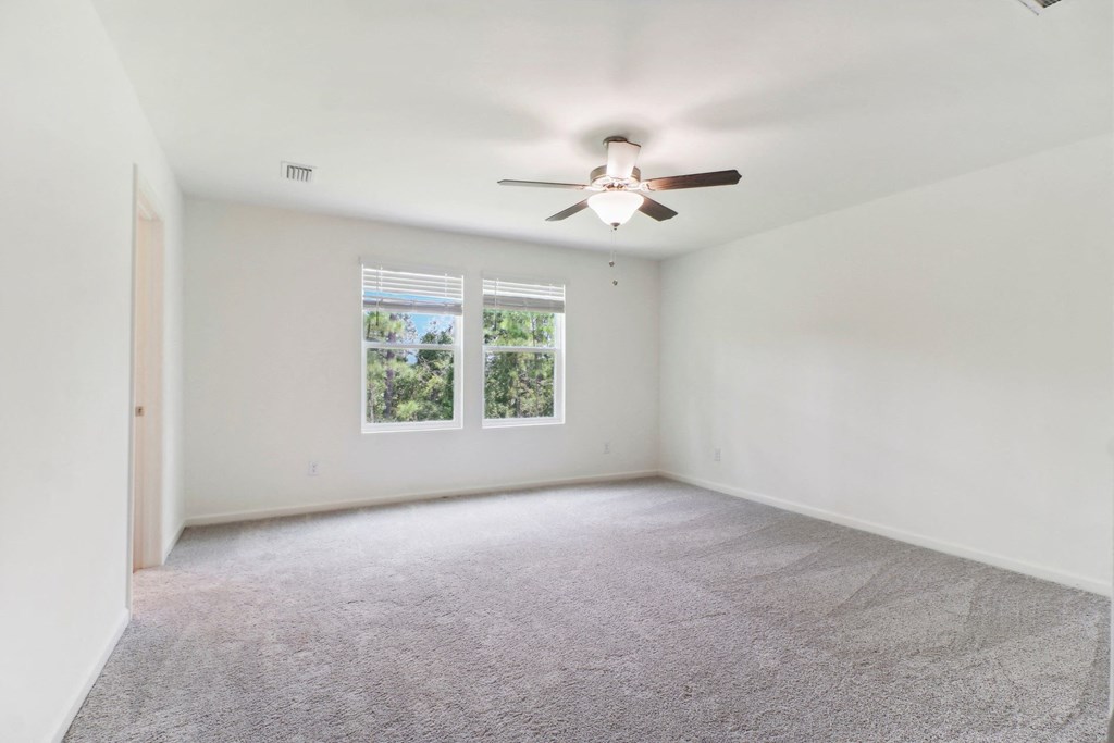 Large master bedroom with ceiling fan and carpet flooring at Beacon at Ashley River Landing in Summerville, SC