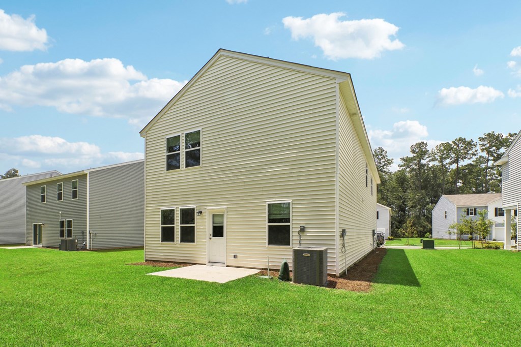 Side view of the house showcasing the expansive backyard and neighboring houses at Beacon at Ashley River Landing in Summerville, SC