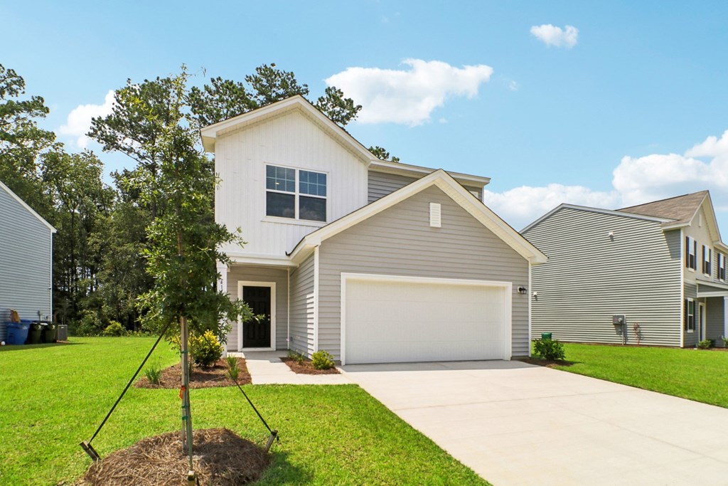 Another front view of a two-story house with a gray and white exterior and a landscaped front yard at Beacon at Ashley River Landing in Summerville, SC