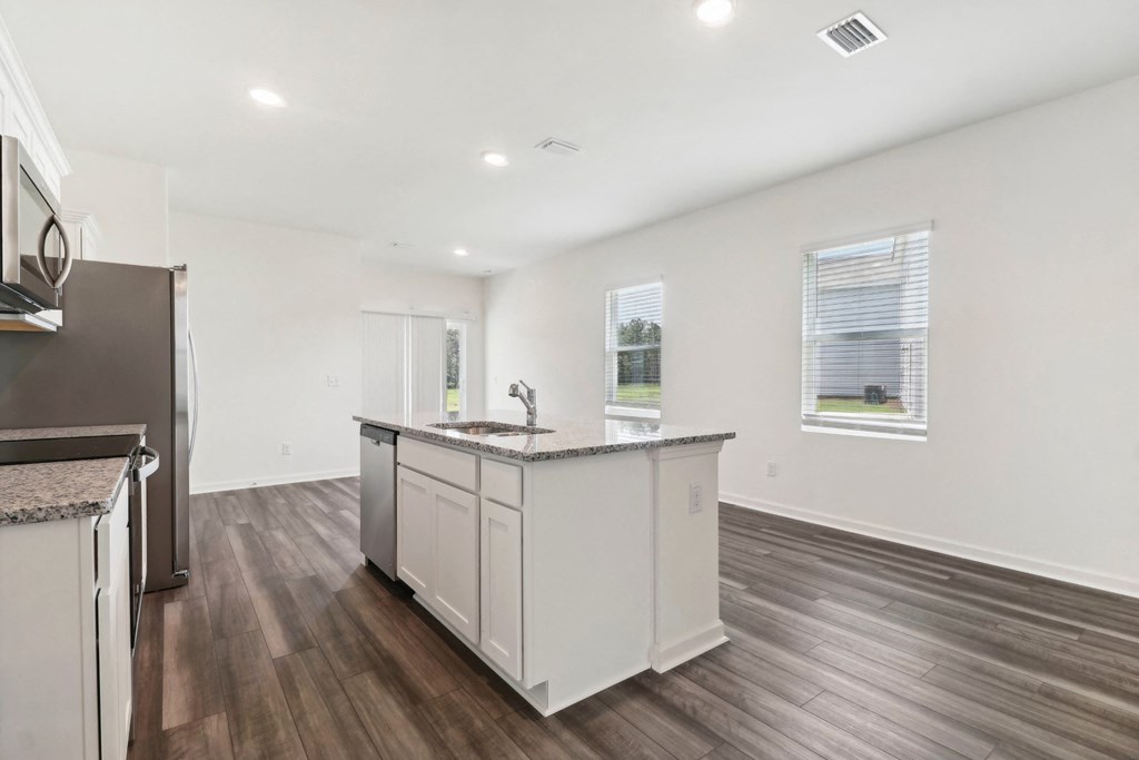 Oak white kitchen with a large island and granite countertop at Beacon at Ashley River Landing in Summerville, SC