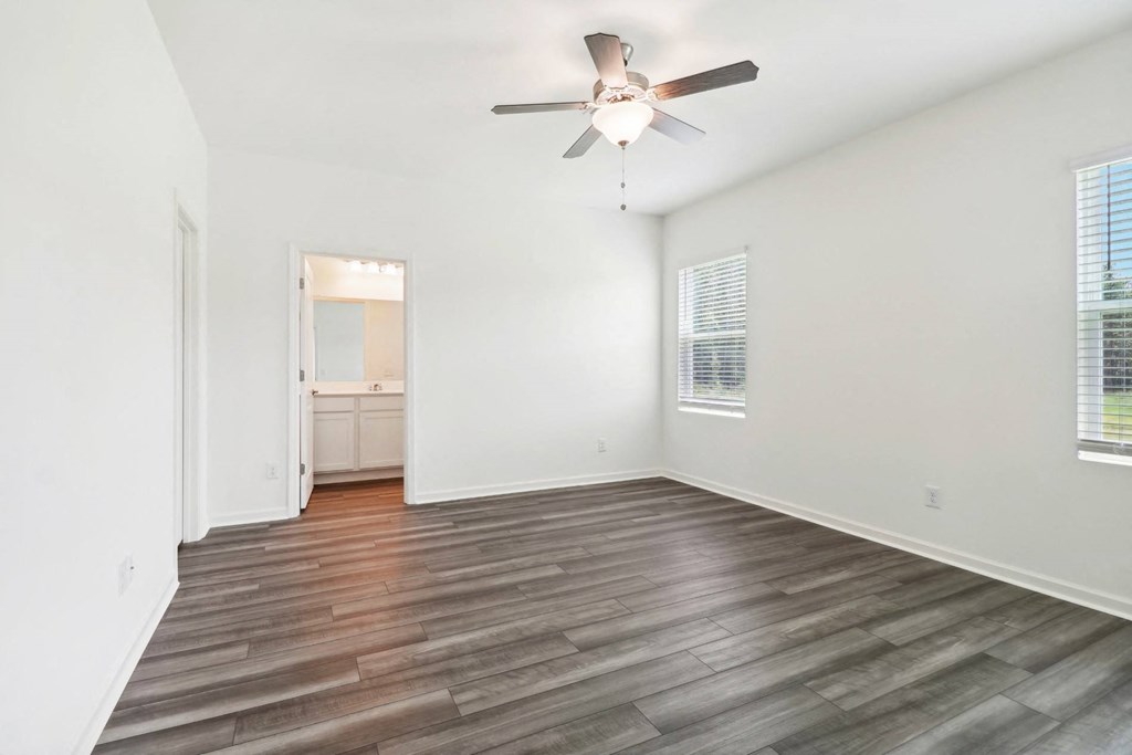 Oak master bedroom with white walls and ceiling fan at Beacon at Ashley River Landing in Summerville, SC