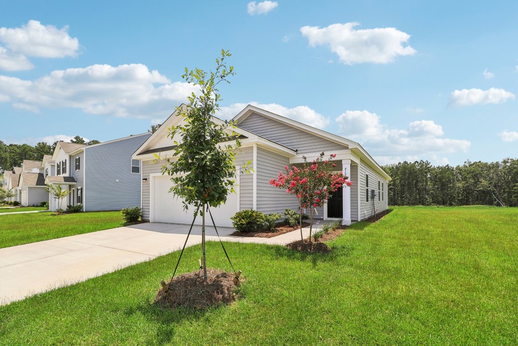 Front entrance and driveway of a single-story house with well-maintained lawn at Beacon at Ashley River Landing in Summerville, SC
