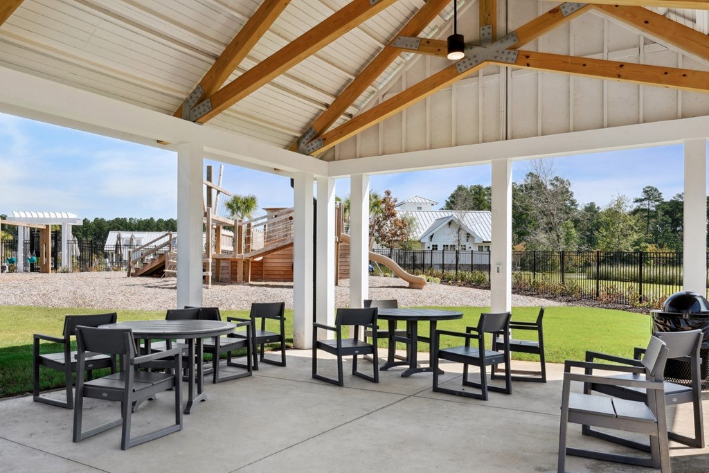 Covered pavilion with tables and chairs and the playground in the background at Beacon at Ashley River Landing in Summerville, SC