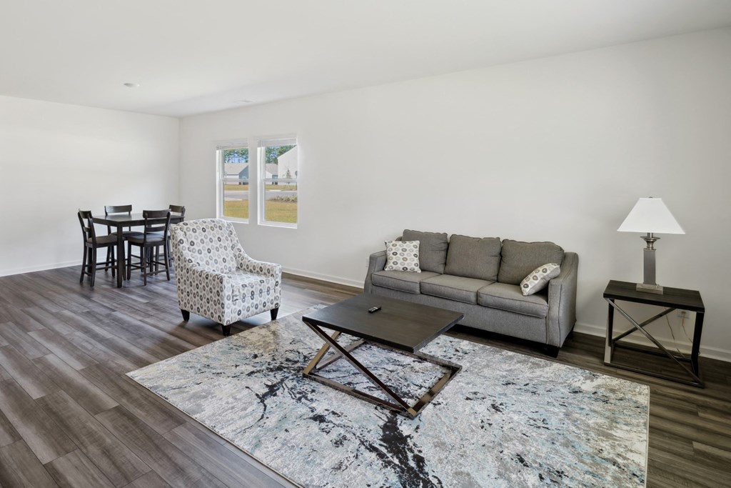 Living room with a couch and chairs and a dining room table in the Poplar floor plan at Beacon at Ashley River Landing in Summerville, SC