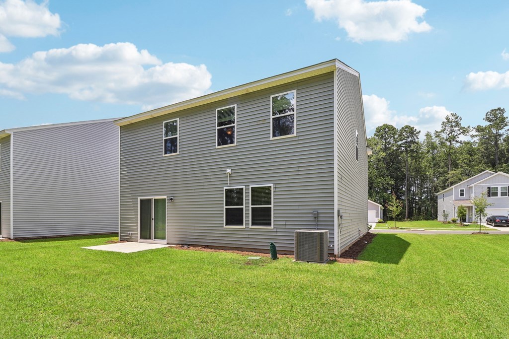 Sycamore back view of a gray house with a green lawn and a blue sky at Beacon at Ashley River Landing in Summerville, SC
