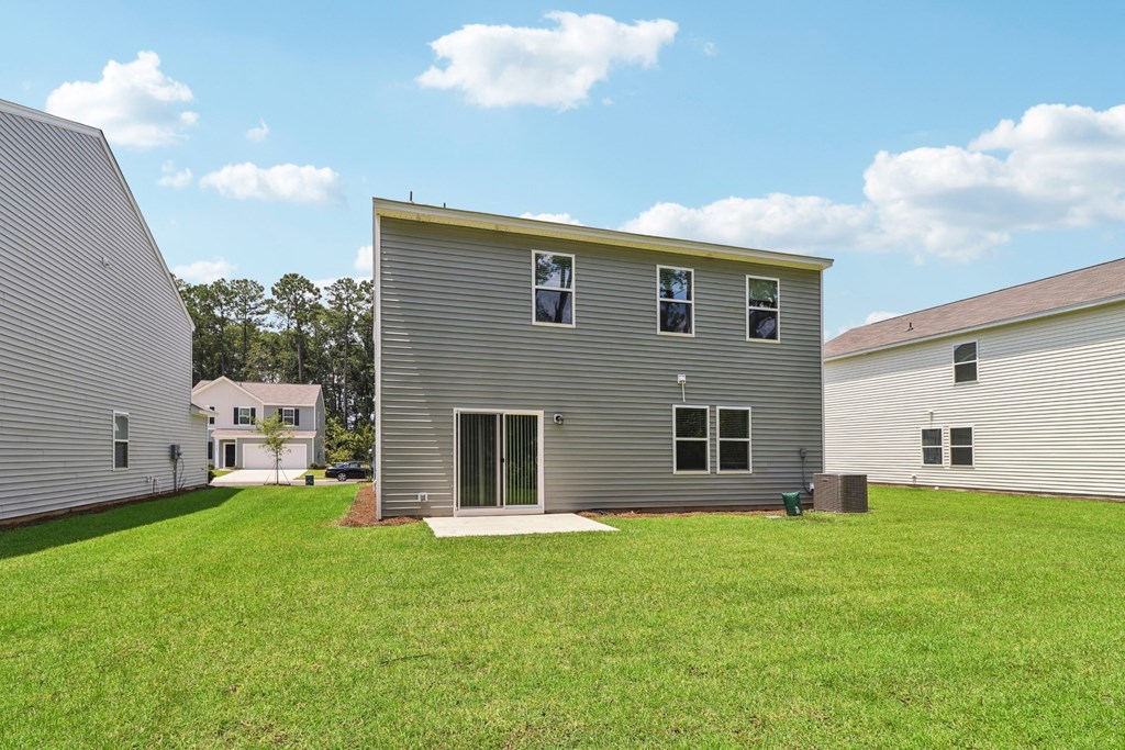 Sycamore backyard with a gray house and a green lawn at Beacon at Ashley River Landing in Summerville, SC