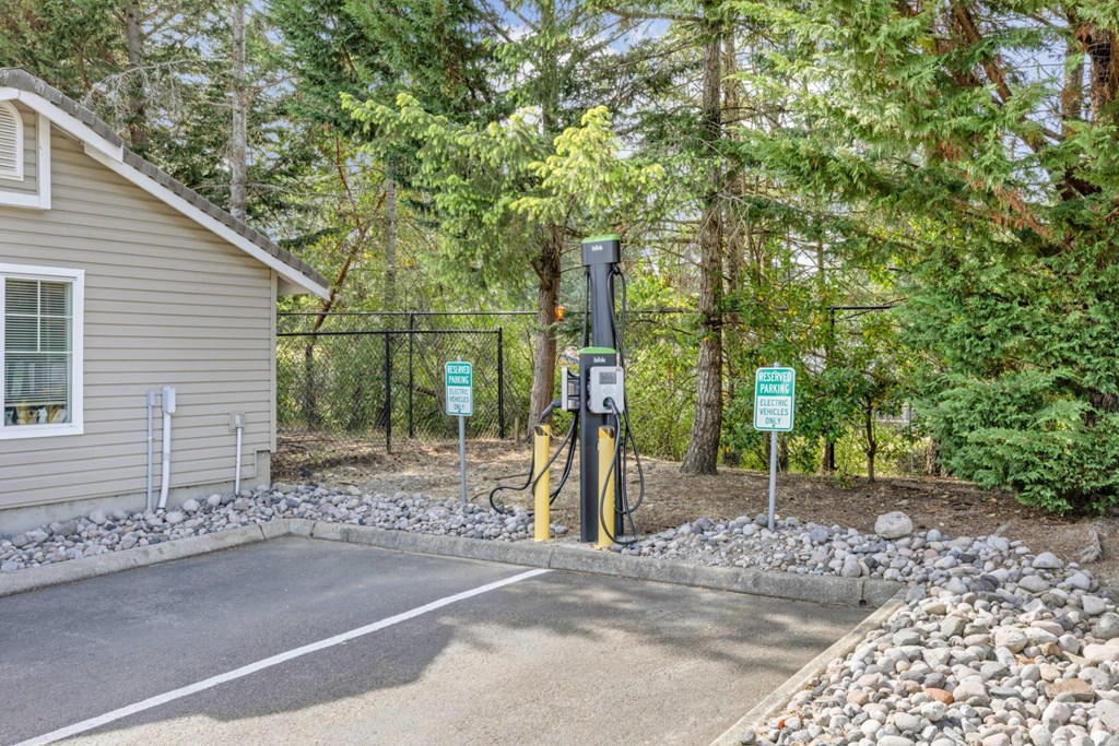 A charging station for electric vehicles with trees in the background at Abbey Rowe Apartments in Olympia, WA