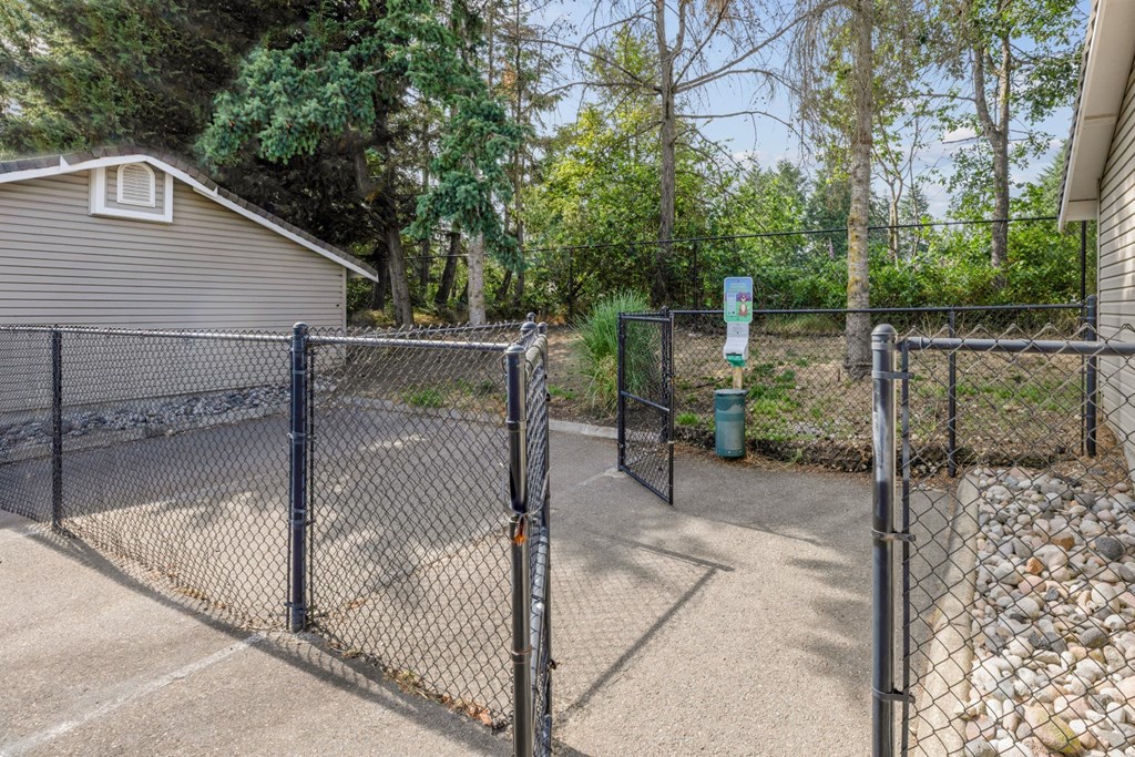 A fenced in pet area with a pet waste station at Abbey Rowe Apartments in Olympia, WA