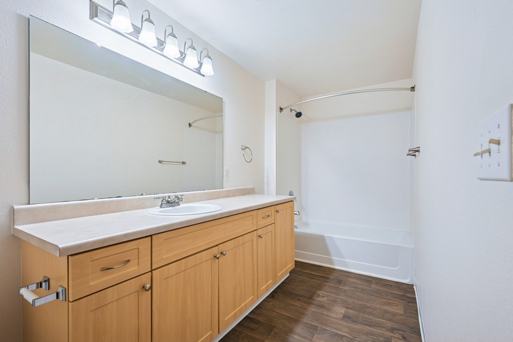 York bathroom with a bathtub and vanity sink with a large mirror and counter at Abbey Rowe Apartments in Olympia, WA
