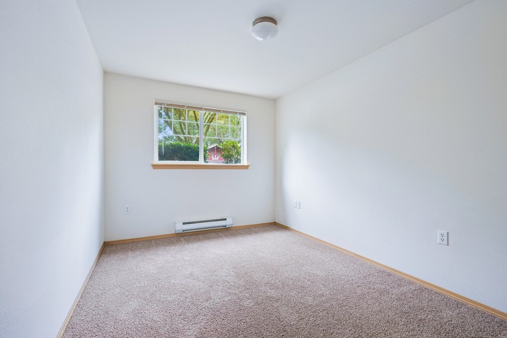 York bedroom with a window and a carpeted floor at Abbey Rowe Apartments in Olympia, WA