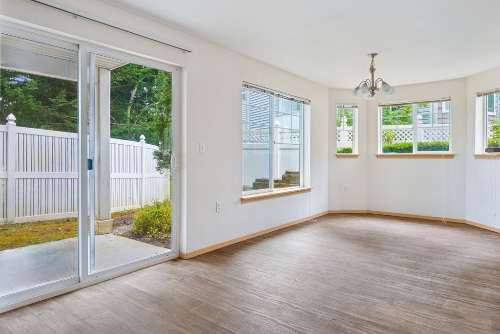 Spacious York dining room with wood floors and glass sliding doors leading to a grassy fenced in patio at Abbey Rowe Apartments in Olympia, WA