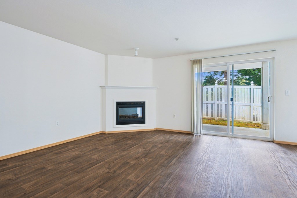 Spacious York living room with a fireplace and sliding glass doors at Abbey Rowe Apartments in Olympia, WA