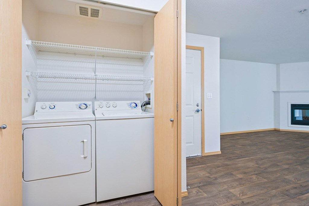 A full size washer and dryer in the York floorplan with the living room in the background at Abbey Rowe Apartments in Olympia, WA