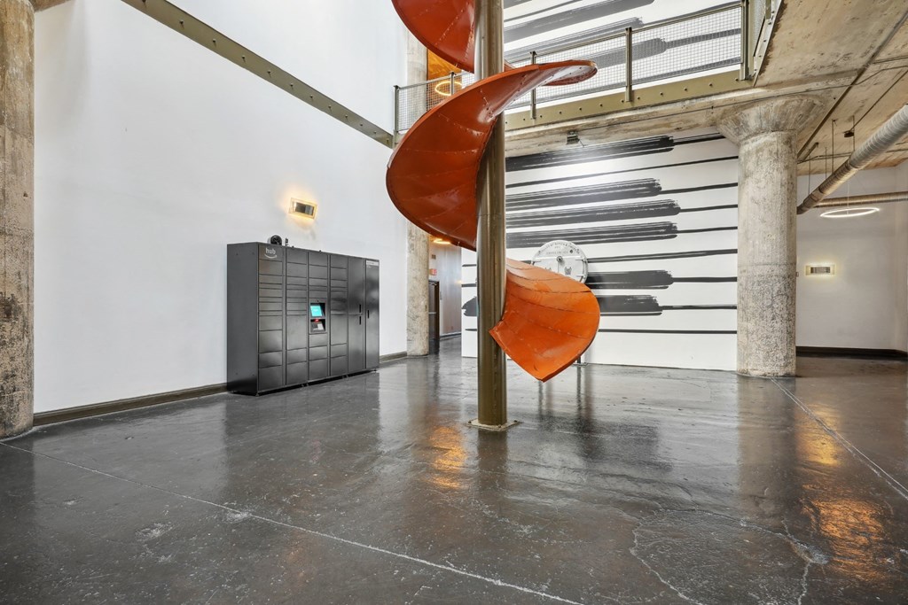Amazon Hub package lockers in atrium next to chute centerpiece from old Ford assembly | Adam Hats Lofts from Deep Ellum Lofts in Dallas, TX