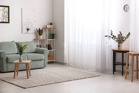 A living room with a green couch, a wooden table, and a painting on the wall.