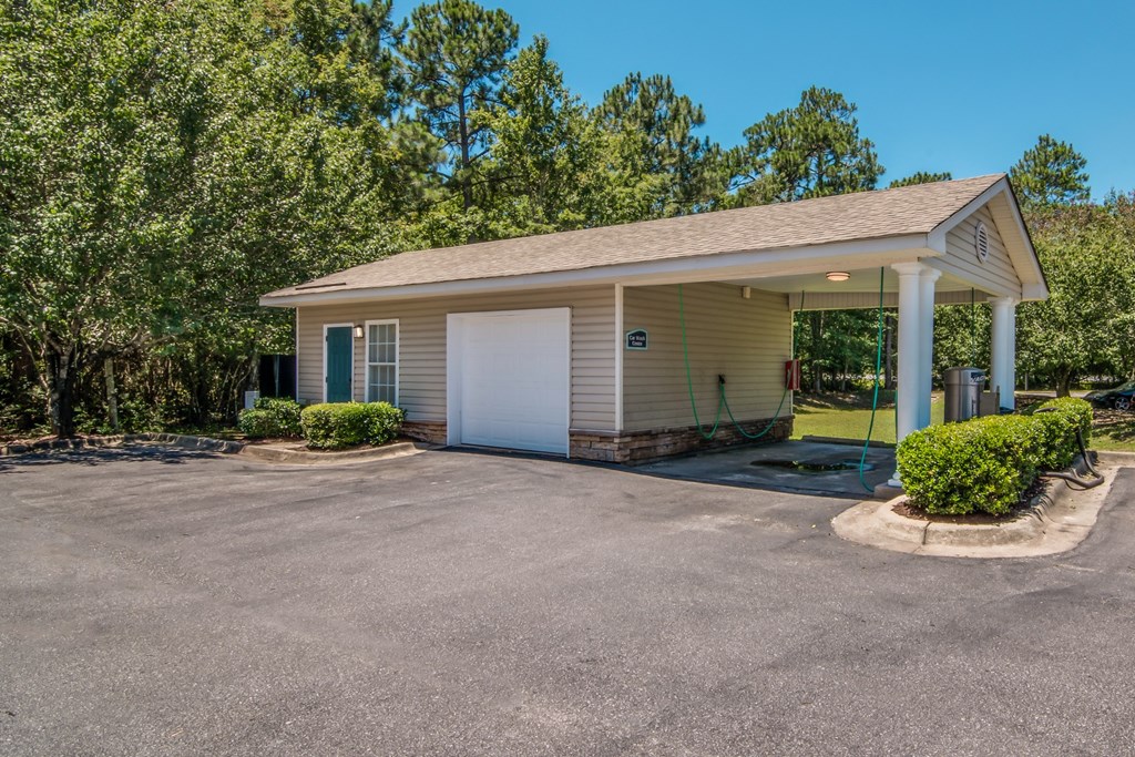 a small white building with a driveway and a car garage