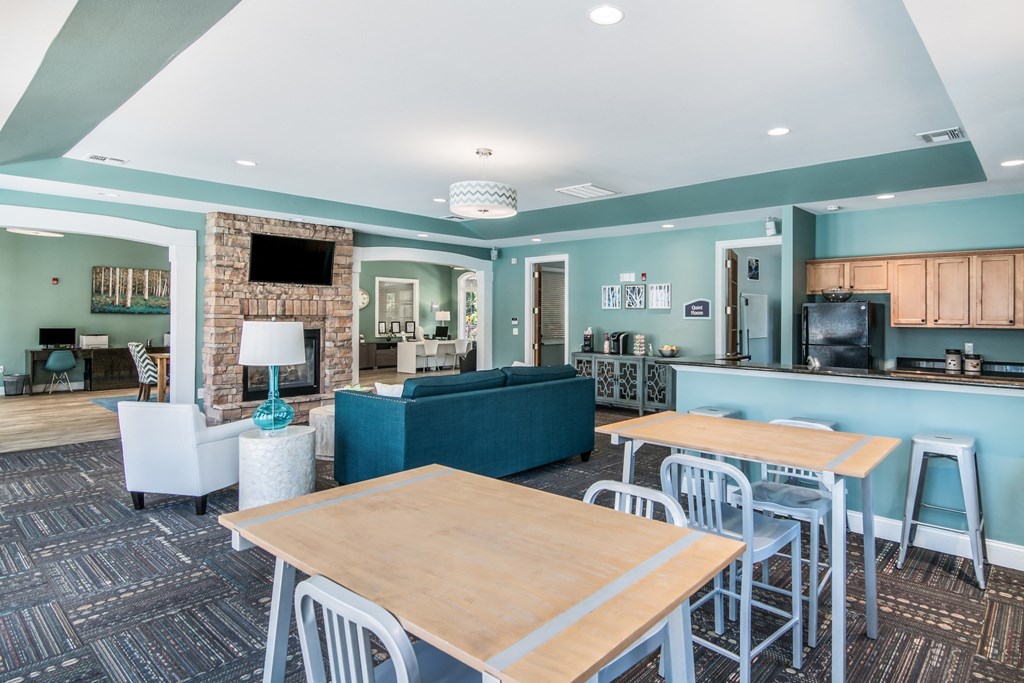 a communal area with tables and chairs and a living room with a blue couch