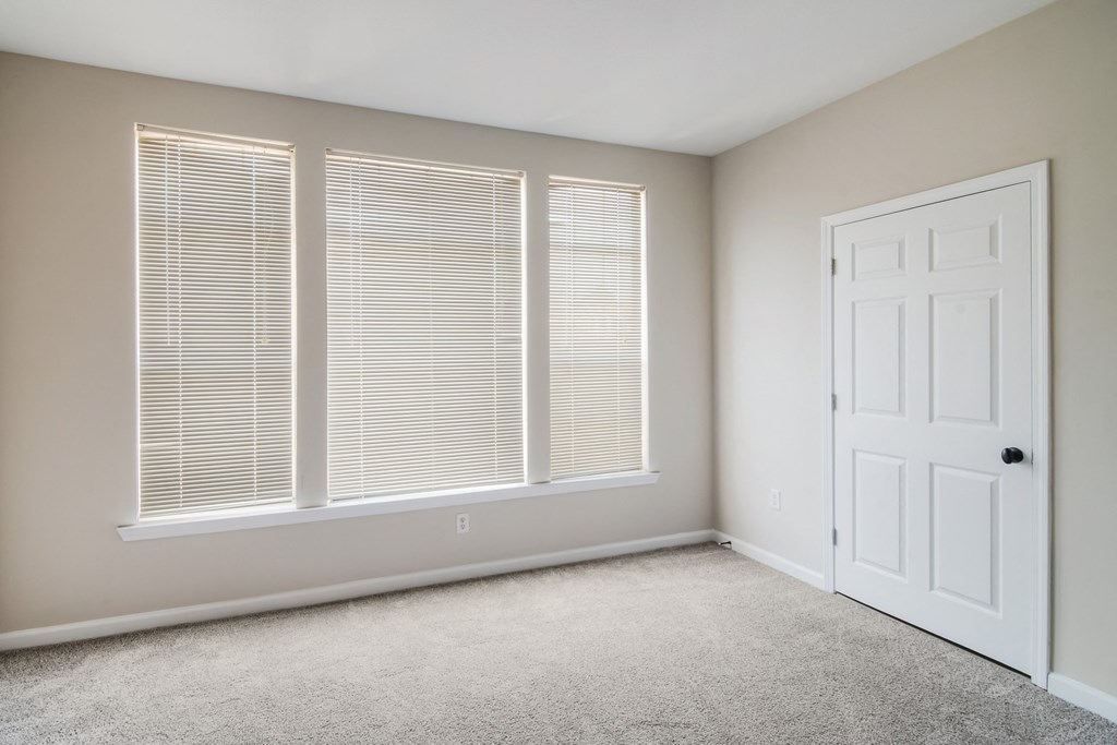 an empty room with three windows and a white door