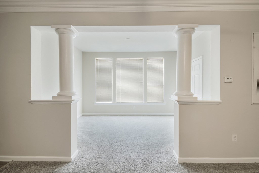an empty living room with columns and a window