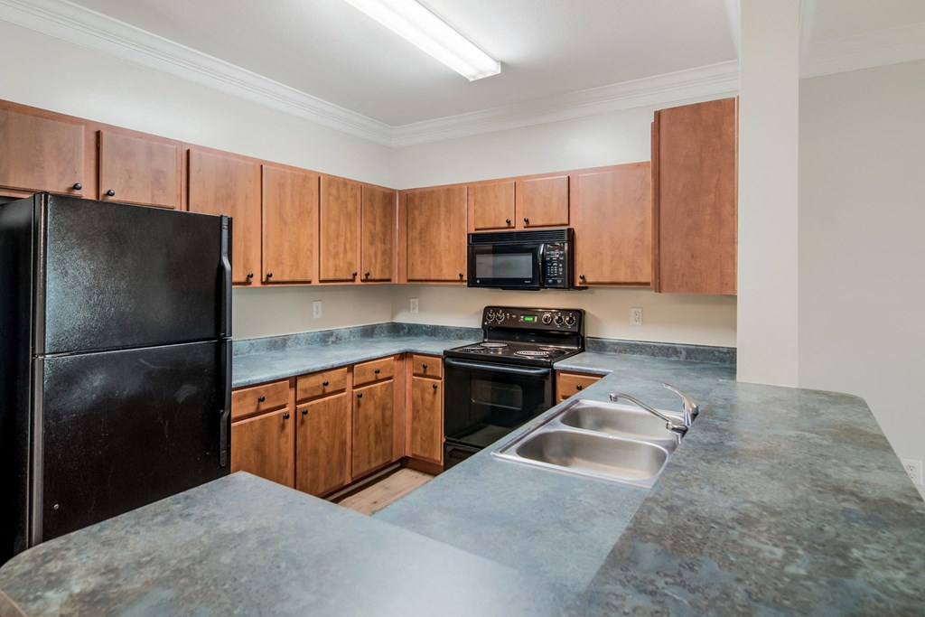 an empty kitchen with granite counter tops and black appliances