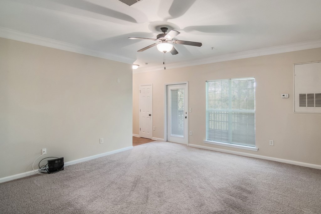 an empty living room with a ceiling fan and a window