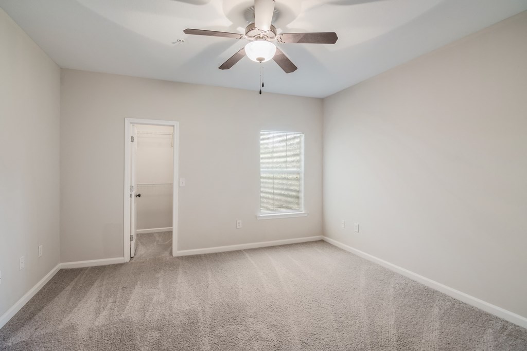 an empty room with carpet and a ceiling fan