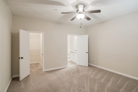 an empty bedroom with a ceiling fan and a closet