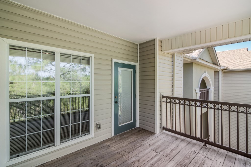the porch of a house with large windows and a balcony