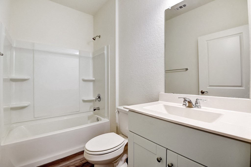 a bathroom with white cabinets, a mirror and white walls