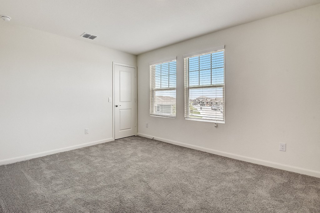 a bedroom with a door and two windows