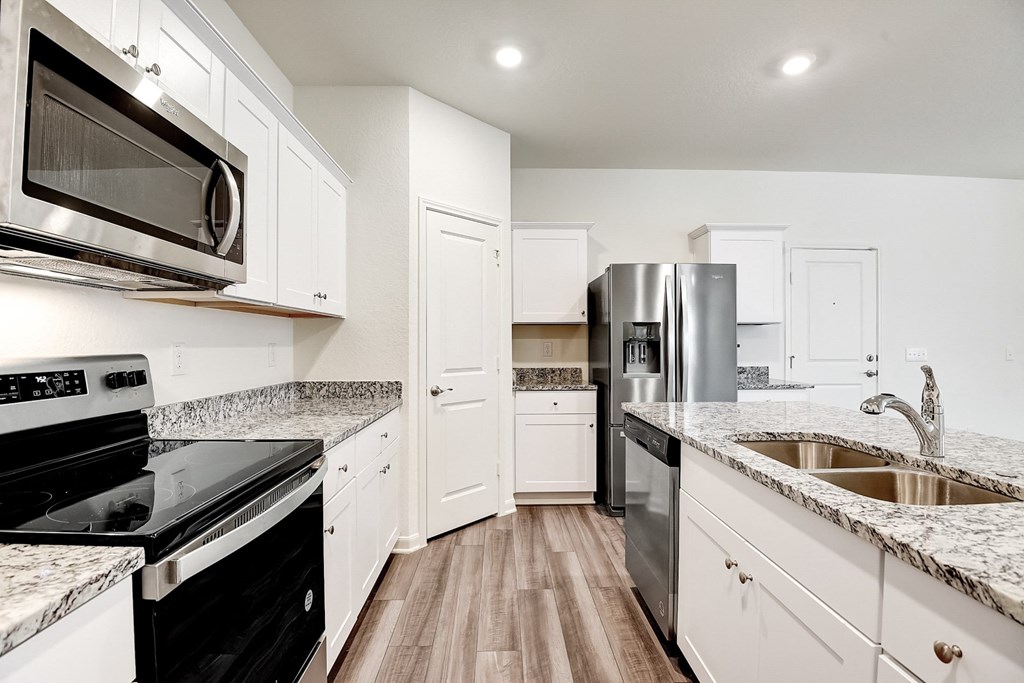 a kitchen with white cabinets and black appliances at Beacon at Meridian, Texas