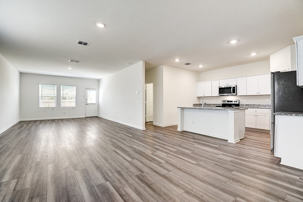 a kitchen and living room with hardwood floors and white walls